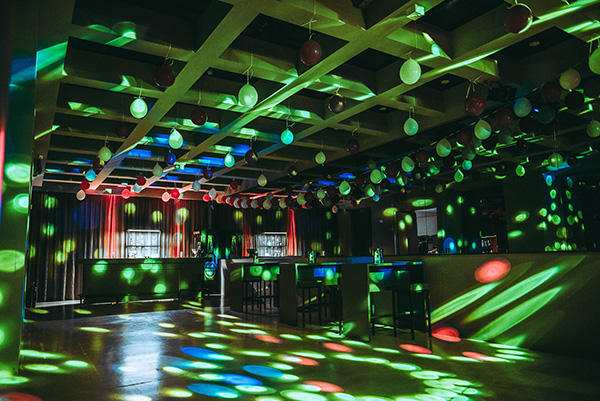 palais-wertheim_lichtanlage_grey-theater - Palais Wertheim Wien Dimly lit nightclub with multicolored disco lights on the floor and ceiling, balloons hanging from the ceiling, and a bar at the back.
