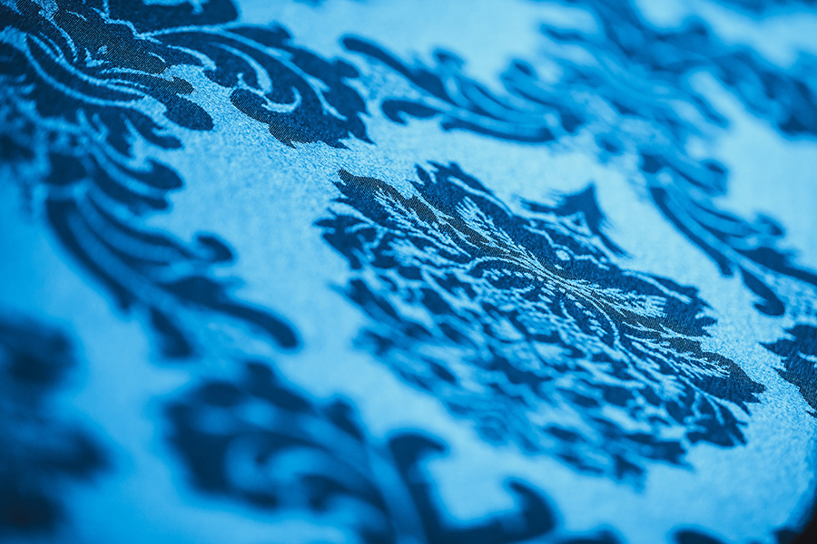 tischtuecher_palais-berg - Palais Wertheim Wien Close-up of a blue damask textile with an ornate floral pattern.
